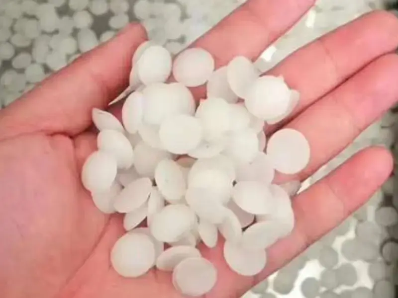 Hand holds soft white pellets for rubber or plastic use.