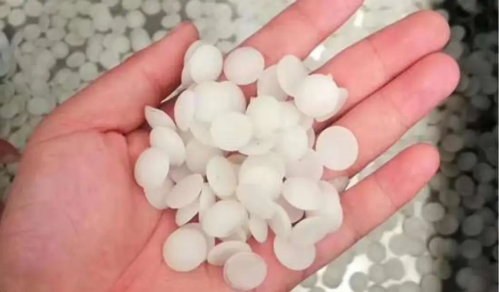 Hand holds soft white pellets for rubber or plastic use.